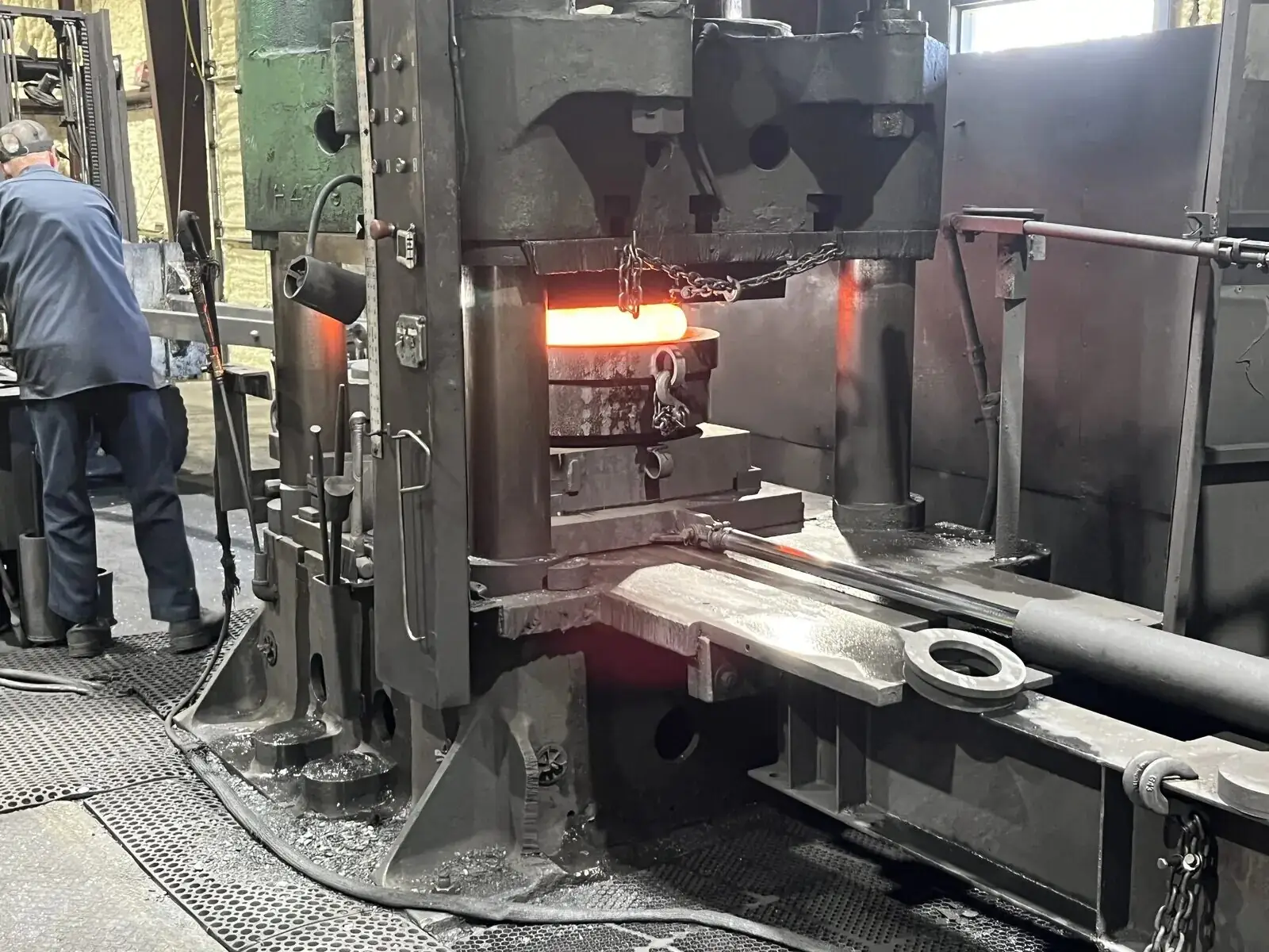 Large custom open-die special forging being manipulated under a hydraulic press
