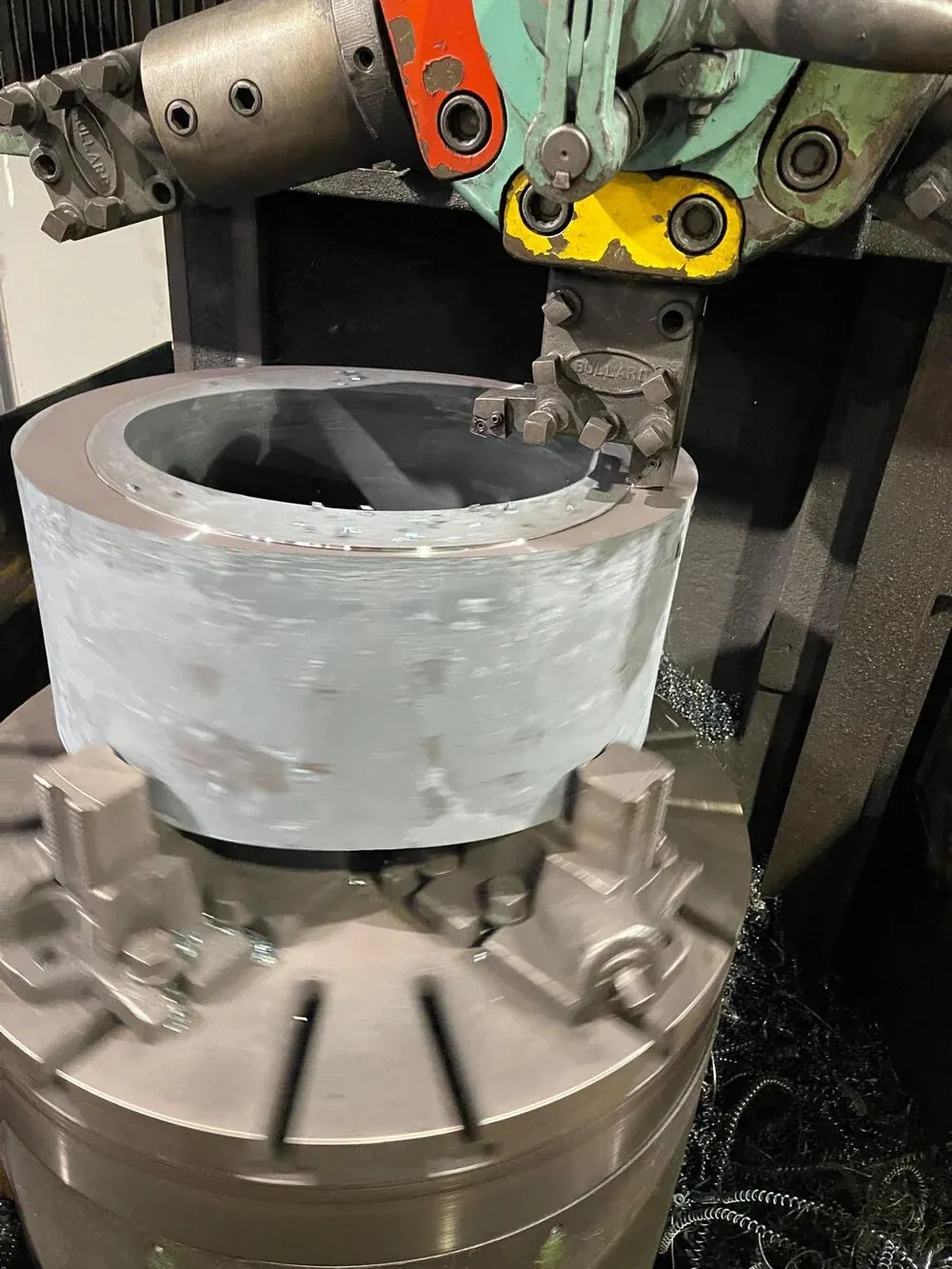 Forged component held in a CNC milling machine being pre-machined to near-net shape